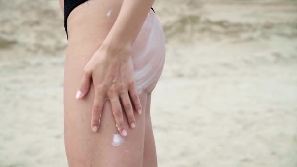 Bikinili genç kız cildine dikkat etmek için kalçalarına ve kalçalarına güneş kremi sürüyor. — Stok video