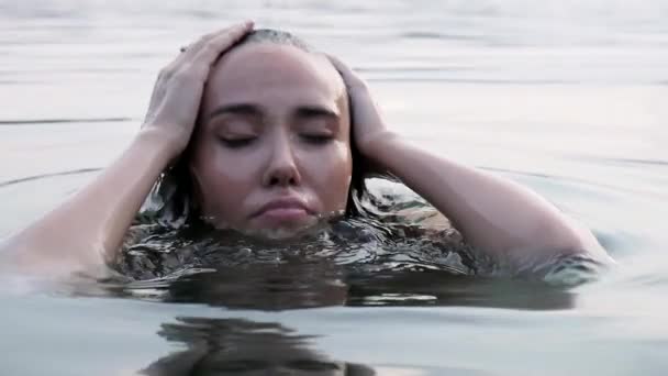 Głowa młodej kobiety, która nurkuje w jeziorze, potem wyskakuje z wody i śmieje się — Wideo stockowe