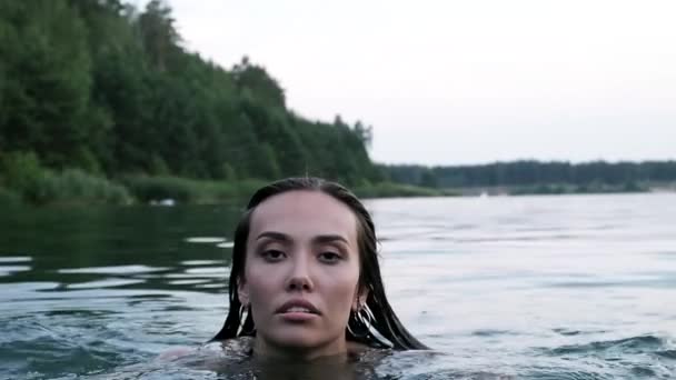 Nahaufnahme im Gesicht einer jungen attraktiven, entspannten Asiatin, die in einem Teich oder See schwimmt — Stockvideo