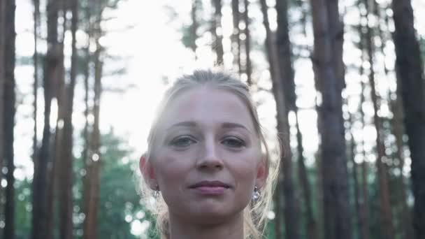 Молодая женщина делает жест намасте в позе лотоса, закрывая глаза в лесу — стоковое видео