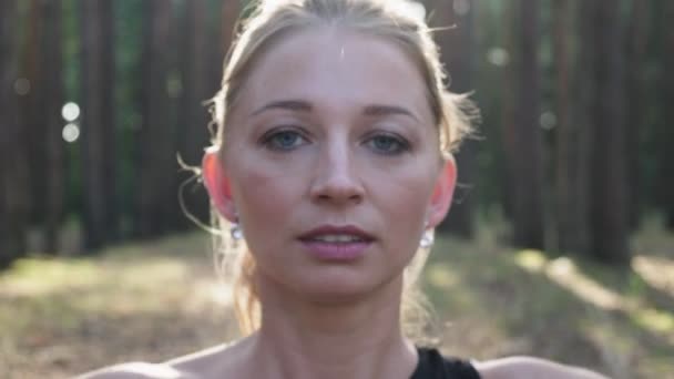Jovem mulher apto fazendo gesto namaste em pose de lótus, fechando os olhos na floresta — Vídeo de Stock