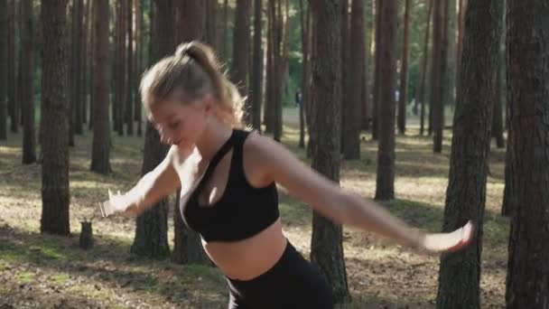 Гнучка підтягнута дівчина практикує йогу, виконує суріа-намаскар в сонячному сосновому лісі — стокове відео
