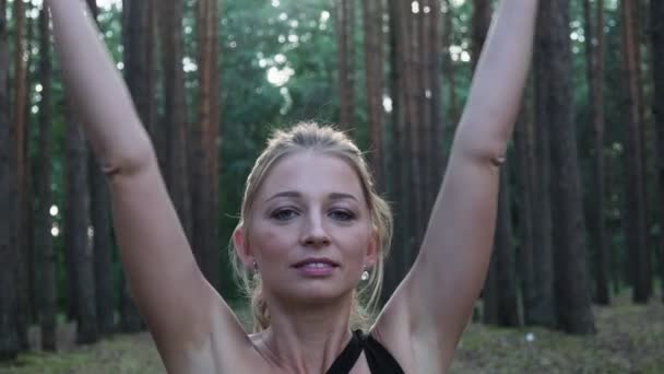 Mladá fit žena dělat namaste gesto v lotosu póza, zavírající oči v lese — Stock video