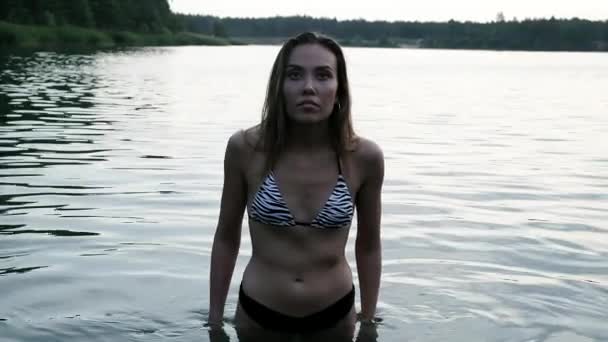 セクシー魅力的な若いですスレンダーなアジアの女の子でストライプゼブラビキニスタンディングで湖 — ストック動画
