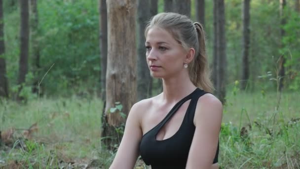 Junge kaukasische Frau sitzt in der Pose eines weisen Mannes namens Marichyasana im Wald — Stockvideo