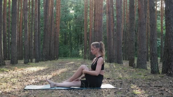 Giovane donna caucasica seduta in posa uomo saggio chiamato marichyasana a foresta — Video Stock