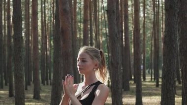 Esnek fit kadın yoga yapıyor, güneşli çam ormanlarında surya namaskar yapıyor.