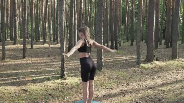 Ajuste flexível senhora pratica ioga, realiza surya namaskar na floresta de pinheiros ensolarada — Vídeo de Stock