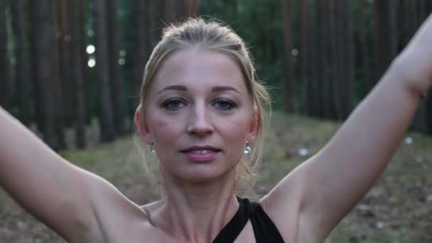 Joven mujer en forma haciendo gesto namaste en pose de loto, cerrando los ojos en el bosque — Vídeo de stock