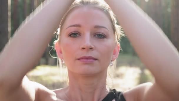 Молодая женщина делает жест намасте в позе лотоса, закрывая глаза в лесу — стоковое видео