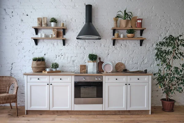 Современный светлый кухонный интерьер с белыми стенами, мебелью, посудой, полками — стоковое фото