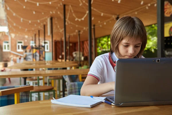 カフェのベランダのテーブルに座ってラテン語を勉強する白人の女の子 — ストック写真