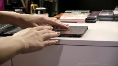 Makyaj sanatçısı aynanın önündeki güzellik salonunda gölge paleti açıyor.