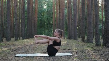 Esnek kadın yoga yapıyor, çam ormanlarında ubhaya padangusthasana yapıyor.