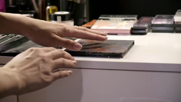 Makeup artist opening powder shadow palette at beauty salon in front of mirror — Stock Video