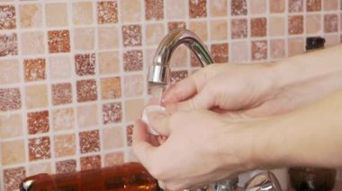 Man washing plastic caps in the sink