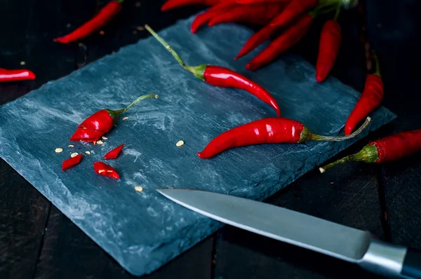 Chilischoten mit Messer auf Küchenbrett schneiden — Stockfoto