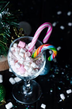 Bir bardak koyu ahşap masa üzerinde beyaz ve pembe şekerleme