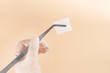 Metal cerrahi kıskaca sıkıştırılmış beyaz bez. Ameliyathanedeki doktorlar için aksesuarlar..