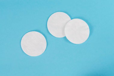 Mavi arka planda beyaz organik pamuklar. Sıfır atık, yeniden kullanılabilir, makyaj temizleyici