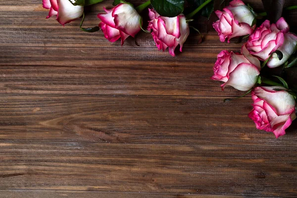 Ahşap kahverengi arka planda güllerin çerçevesi. Fotokopi alanı olan bir kartpostal konsepti, düz konum