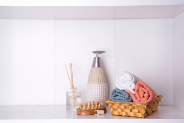 Ahşap tepside havlular aroma çubukları, mumlar, deniz kabukları, masaj bezleri ve içinde şeker kutusu olan bir şişe.