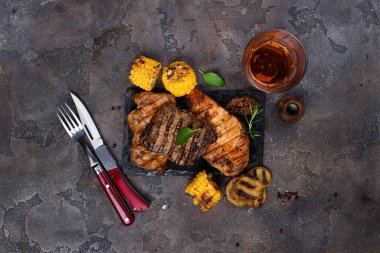 Üç çeşit ızgara biftek (tavuk, domuz, sığır eti), otlar, meyve suyu ve ızgara patatesle birlikte, arka planda fotokopi alanı ve düz bir tabakta.