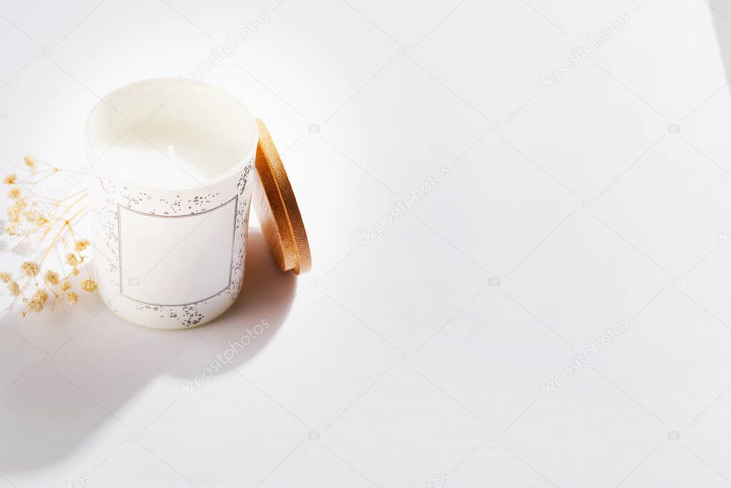 Soy candles in white glass bottles with cover and dry flower, on a white background.