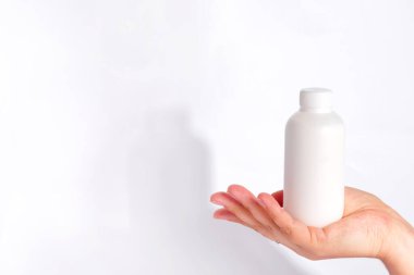 Beyaz arka planda el ele tutuşan krem ya da losyon şişesi
