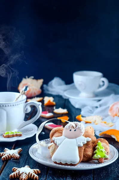 Teacup with tea and biscuits angel, tangerineon a black table — Stock Photo, Image