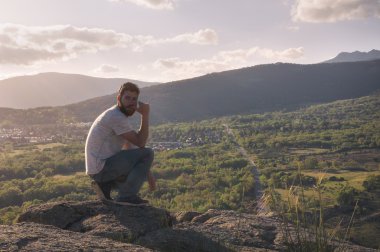 Rahat genç adam dağın zirvesinde Sigara