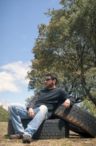 Mężczyzna siedzący na koła samochodów ciężarowych w lesie — Zdjęcie stockowe