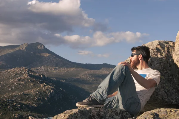 Relaxado jovem tomando banho de sol no topo da montanha — Fotografia de Stock