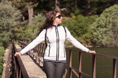 Orman ve göl üzerinde arka plan ile köprüde genç kadın 