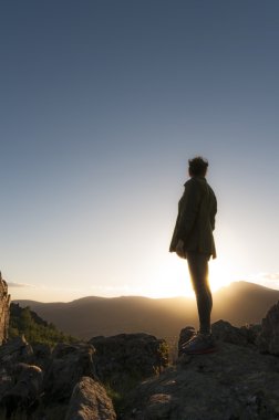 Dağın tepesinde gün batımını izlemek kız. Dikey