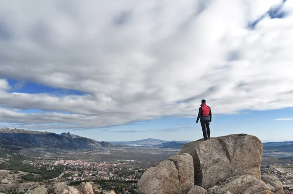 Man on the top of the peak watching the city — Stock Photo, Image