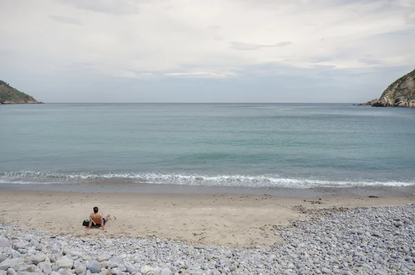Uomo sdraiato sulla spiaggia segreta di sabbia — Foto Stock