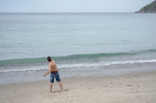 Man plays throwing rocks at the beach — Stock Photo, Image