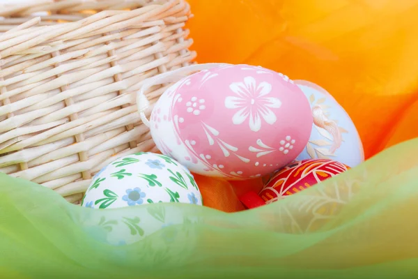 Close-up of strawy basket with Easter eggs and velvet — Stock Photo, Image