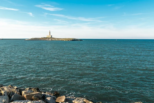 Faro monumental en pequeña isla rodeada de mar azul — Foto de Stock