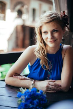 Beautiful young woman posing to photographer at the table