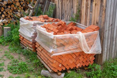 Eski tuğlalar paletlere konur ve naylona sarılır. Yatay resim.