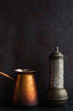 Geleneksel Türk kahve ve konsepti. Bakır kahve demliği. Cezalı, eskimiş kahve öğütücüsü koyu bir arka planda.