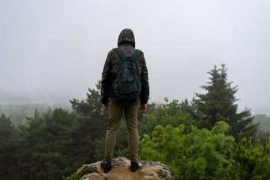 Orman manzaralı bir dağın tepesinde duran bir adam Seyahat tarzı macera tatili konsepti