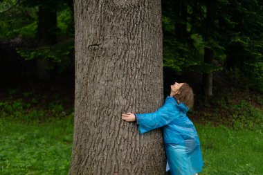 Yaz ormanında ağaç gövdesine yaslanan genç bir kadın..