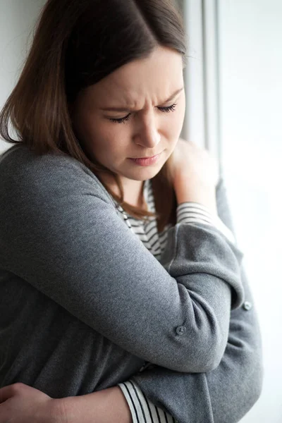 Sorgsen Ser Ung Kvinna Står Vid Fönstret Vit Bakgrund — Stockfoto