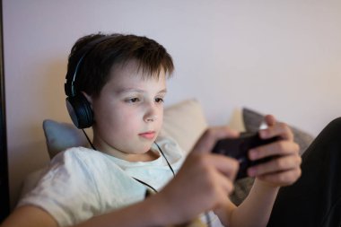 Akıllı telefonuyla video oyunu oynayan 10 yaşında bir çocuk.