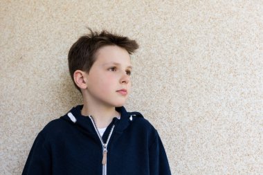 Duvara dayanmış 10 yaşındaki bir çocuğun portresi.