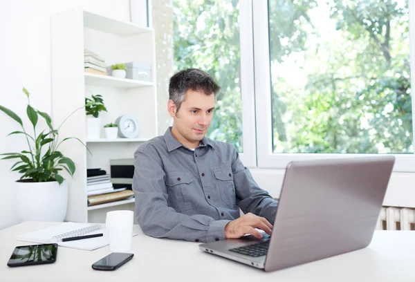 Jeune homme au bureau, travaillant sur ordinateur portable — Photo
