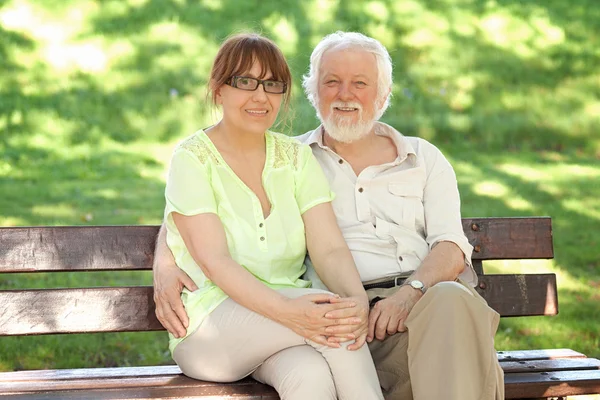Starszy para siedzi na ławce w parku — Zdjęcie stockowe